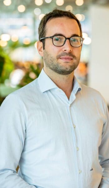 Marco Li Mandri, Head of Advanced Analytics Strategy der ING Gruppe, präsentiert sich in einem modernen Büroambiente. Der Hintergrund ist unscharf, mit sanften Lichtakzenten und grünen Pflanzen, die eine angenehme Atmosphäre schaffen.