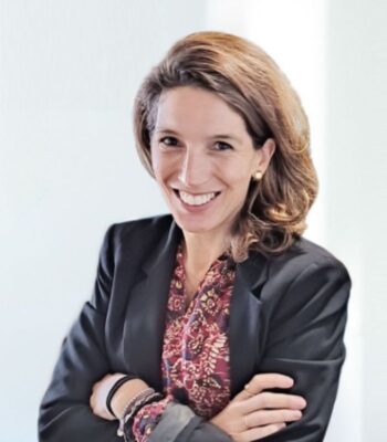 Lourdes Bustos, ehemalige EU-Kommissionspolitikerin, lächelt und steht mit verschränkten Armen in einem professionellen Umfeld. Raquest hat sie in das Advisory Board berufen, um ihre Expertise einzubringen.