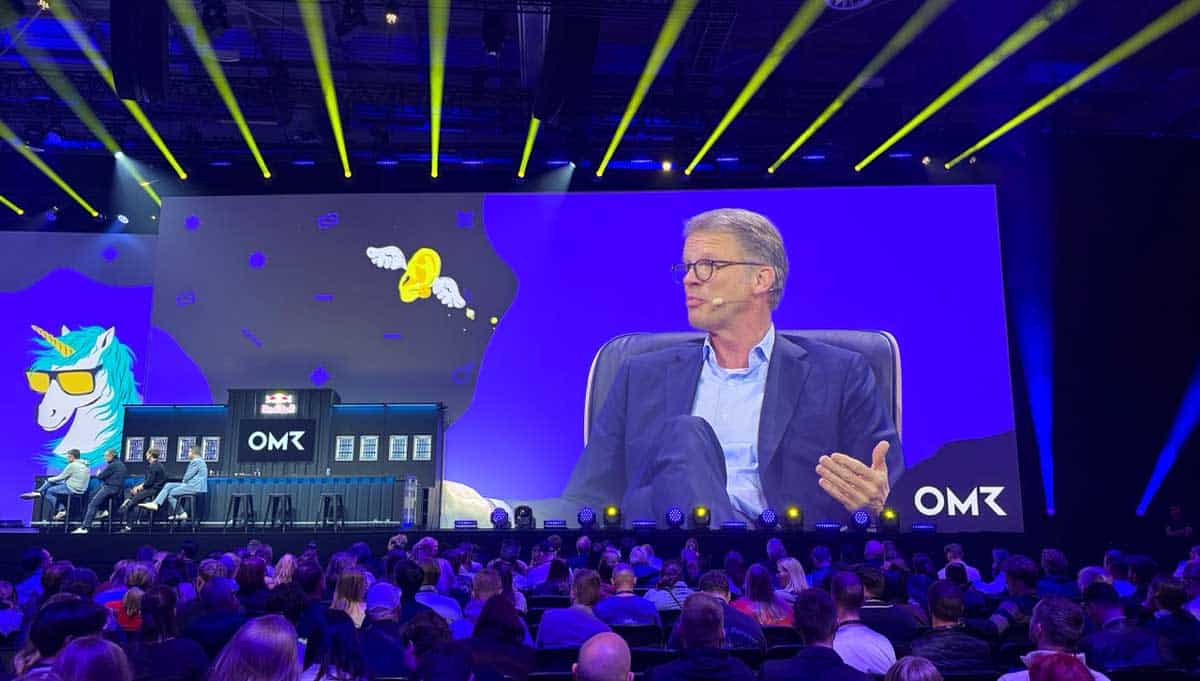 Karsten Wildberger, Bundesminister für Digitales und Staatsmodernisierung, spricht auf der Conference Stage des OMR-Festivals 2026. Im Hintergrund sind kreative Grafiken und eine große Zuschauerzahl zu sehen, die das Event umrahmen.