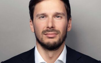 Benjamin Tenke, Senior Architect bei Cofinpro, präsentiert sich in formeller Kleidung. Sein neutraler Gesichtsausdruck und der direkte Blick unterstreichen Professionalität. Die Thematik der Wiederverwendung in IT-Architekturen könnte in seinem Kontext von Bedeutung sein.