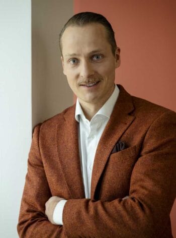 Nikolaus Trzeschan, Country Manager Deutschland bei Mastercard, präsentiert sich in einem braunen Blazer vor einem neutralen Hintergrund. Der Fokus liegt auf seiner Rolle in der Einführung von KI-Agenten für sichere, transparente Zahlungen.