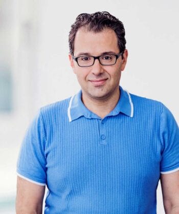 Oleg Wjazemski, Financial Services SAS, präsentiert sich in einem blauen Poloshirt. Der Kontext verweist auf die Herausforderungen der Scam-Erkennung, die als architektonische Fragestellung betrachtet werden sollte, um den finanziellen Verlusten entgegenzuwirken.