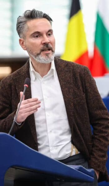 Fabio De Masi, Mitglied des Ausschusses für Wirtschaft und Währung des Europäischen Parlaments, spricht über die Herausforderungen der digitalen Souveränität Europas im Kontext des globalen Finanzsystems. Im Hintergrund sind Flaggen europäischer Länder sichtbar.