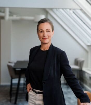 Emma Bauer, neue Chief Product Officer von Signicat, präsentiert sich in einem modernen Büro. Sie trägt einen schwarzen Blazer und ein schwarzes Oberteil, während sie selbstbewusst in die Kamera blickt. Der Hintergrund zeigt einen hellen, offenen Raum.
