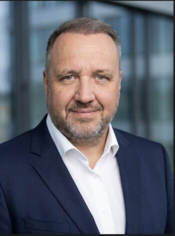 Jens Hillmer, HDI Global, präsentiert sich in einem professionellen Umfeld. Der Fokus liegt auf der strategischen Ausrichtung des Unternehmens zur Integration von Künstlicher Intelligenz in die Digitalisierungs- und Innovationsstrategie zur Verbesserung des Kundenservices.