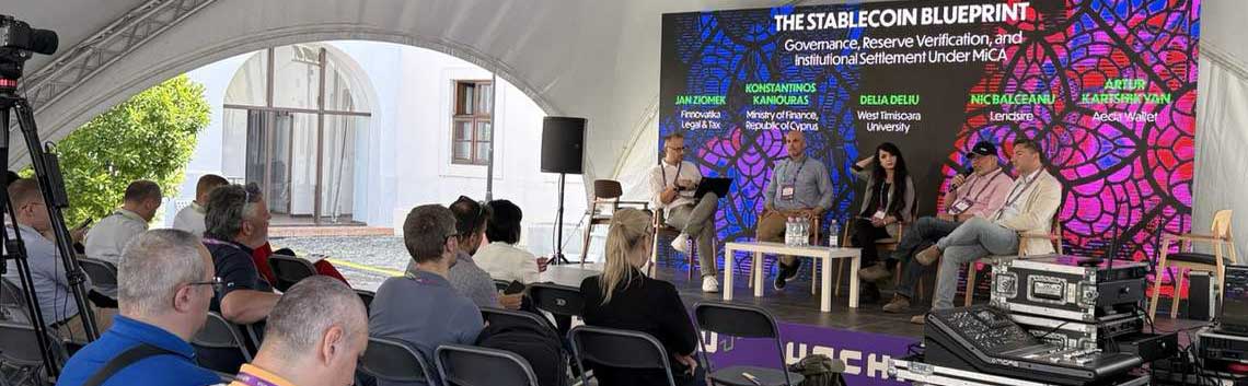Auf der UNCHAIN 2026 Forum Stage diskutieren Experten über Governance und institutionelle Abwicklung im Kontext von Stablecoins. Im Hintergrund sind technische Geräte und eine farbenfrohe Präsentation sichtbar, während das Publikum aufmerksam zuhört.