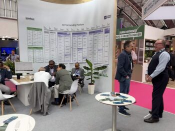 Auf der Money20/20 sind Fachleute an einem Stand versammelt, um über die AI-First Lending Platform zu diskutieren. Im Hintergrund sind Informationsmaterialien und Präsentationen sichtbar, die die Innovationskraft im Finanzsektor unterstreichen.