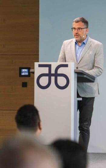 Ulrich Coenen, Vorstandssprecher von Atruvia, präsentiert auf der Hauptversammlung. Im Hintergrund ist das Logo von Atruvia sichtbar. Der Fokus liegt auf der strategischen Weiterentwicklung der genossenschaftlichen Banken durch Hybrid-Cloud und KI.