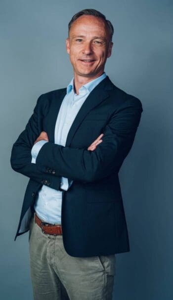 Dirk Littig, Co-Geschäftsführer von Conda Capital Market, präsentiert sich in formeller Kleidung. Die Tokenisierung von Finanzinstrumenten wird durch das elektronische Wertpapiergesetz (eWpG) unterstützt, das die digitale Emission fördert.