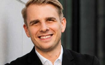 Jan von Ketelhodt, ein Experte im Bereich Agentic Commerce, lächelt in die Kamera. Sein Auftreten vermittelt Professionalität und Offenheit. In diesem Kontext wird die Bedeutung von Transaktionen im digitalen Handel hervorgehoben.