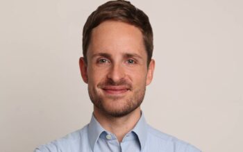Dr. Jonas Groß, Geschäftsführer der Etonec, präsentiert sich in einem professionellen Porträt. Seine Expertise in der Zahlungsinfrastruktur und den Potenzialen von Stablecoins wird durch sein Lächeln und die formale Kleidung unterstrichen.
