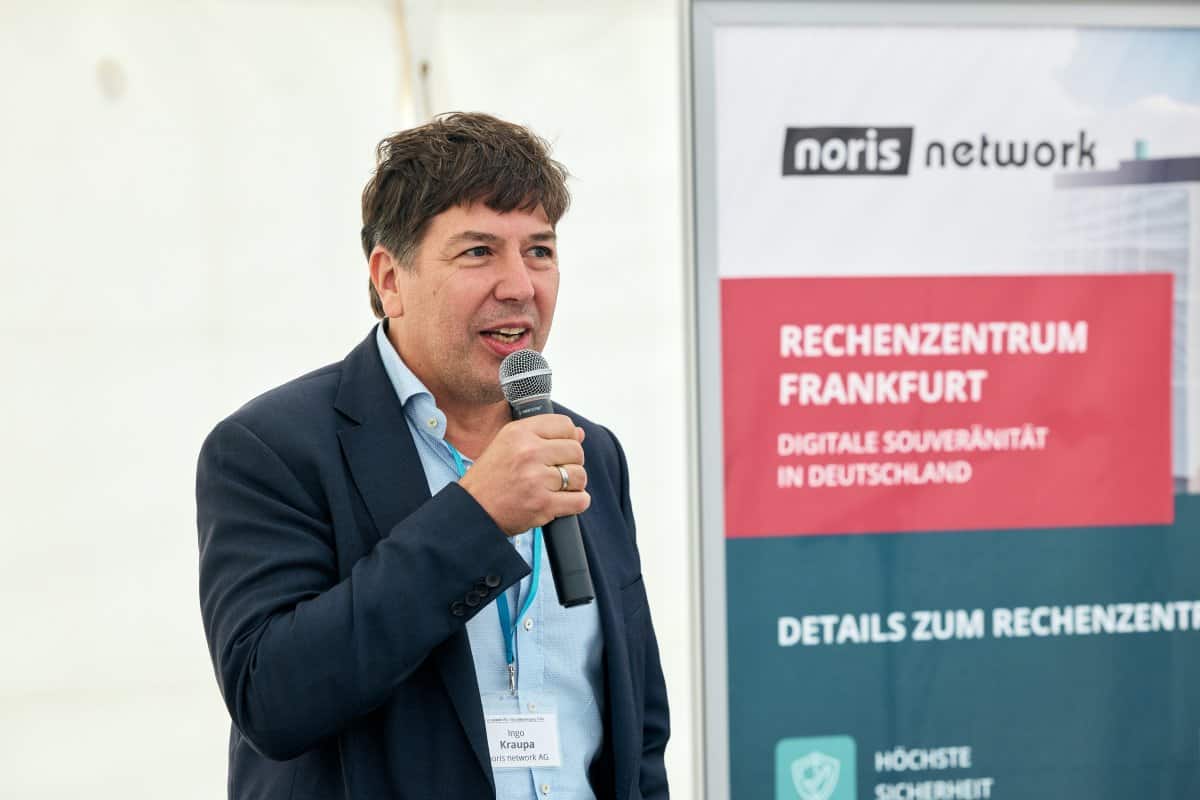 Ingo Kraupa, CEO von Noris Network, spricht auf einer Veranstaltung zum neuen Rechenzentrum in Frankfurt. Im Hintergrund ist ein Banner mit Informationen über digitale Souveränität und Sicherheitsstandards zu sehen.