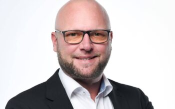 Sebastian Kolter, Senior Director Banking bei Diebold Nixdorf, präsentiert sich in einem professionellen Porträt. Seine langjährige Erfahrung in der Finanzdienstleistungs- und Bargeldmanagement-Branche wird durch sein Auftreten unterstrichen.