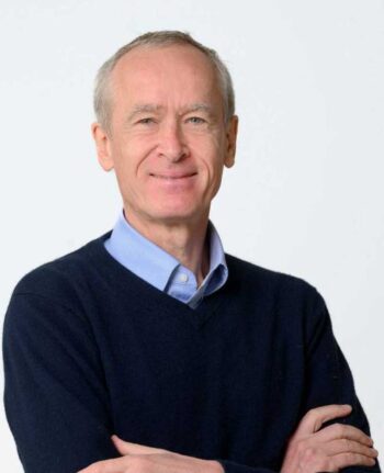 Christoph Burger, Senior Lecturer an der ESMT Berlin, präsentiert sich mit verschränkten Armen und einem freundlichen Lächeln. Der neutrale Hintergrund unterstützt die Fokussierung auf seine Person, die im Kontext der Diskussion über KI-Agenten relevant ist.