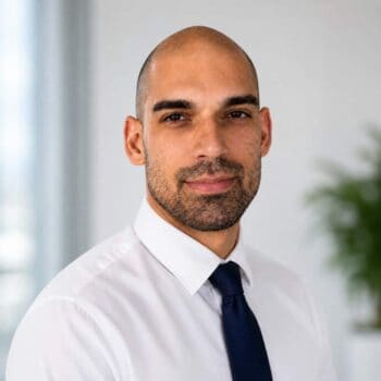 Antonio Paolo Mecci, ein Fachmann im Bereich Krypto-Inventar, präsentiert sich in formeller Kleidung. Der Hintergrund ist hell und modern, was auf eine professionelle Umgebung hinweist. SecureSafe wird als mögliche Lösung für die Verwaltung von Krypto-Daten erwähnt.
