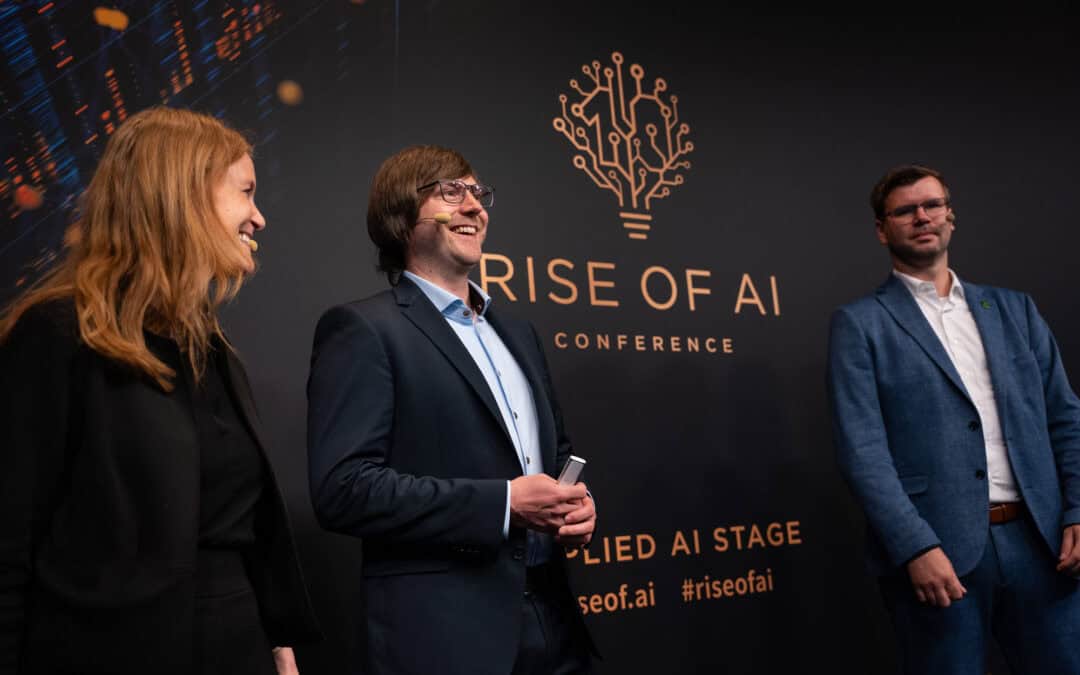 Dr. Anna Gründler, Dennis Geisse und Dr. Robert Friedrich stehen auf der Bühne der Rise of AI-Konferenz. Die Präsentation thematisiert Innovationen im Bereich Cloud und Künstliche Intelligenz.