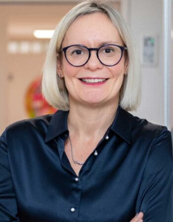 Sandra Dury, Geschäftsführerin von Dury Consult, präsentiert sich in einem professionellen Umfeld. Im Kontext von „Privacy by Design“ wird die Bedeutung des Datenschutzes bei der Implementierung neuer Technologien wie CRM-Systemen und KI-Assistenten hervorgehoben.