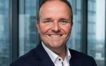 Dr. Thomas Lindner, Managing Director bei flatexDEGIRO, ist abgebildet. Er beschäftigt sich mit der technischen und organisatorischen Weiterentwicklung von Finanzprozessen in einem regulierten Bankenumfeld. Der Hintergrund zeigt moderne Büroarchitektur.
