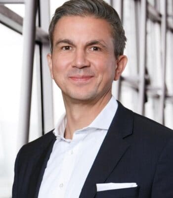Felix Miederer, neuer Co-CEO von SWIAT, präsentiert sich in formeller Kleidung vor einem modernen architektonischen Hintergrund. Sein freundlicher Ausdruck und die professionelle Haltung unterstreichen seine Rolle in der Unternehmensführung.
