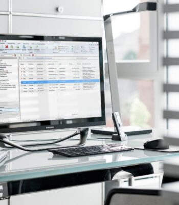 Ein Computerbildschirm zeigt eine Softwareanwendung zur Verwaltung von Zahlungsverkehrsdaten. Auf dem Bildschirm sind mehrere Transaktionen aufgelistet, die Datum, Betrag und Empfängerinformationen enthalten. Der Arbeitsplatz ist modern und gut beleuchtet.
