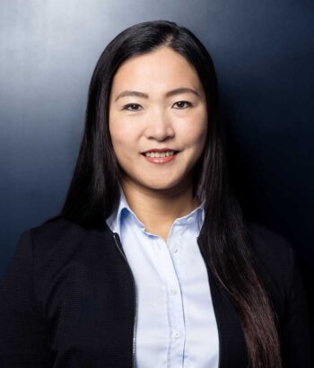 Yiping Li, Chief Operating Officer der Privatbank der Deutschen Bank, präsentiert sich in einem professionellen Umfeld. Ihr Ausdruck vermittelt Entschlossenheit und Engagement für die bevorstehenden Veränderungen in der Kernbankeninfrastruktur.