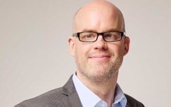 Florian Bongartz, Senior Business Development Manager bei PPI, präsentiert sich in einem professionellen Umfeld. Seine Expertise in digitalen Systemen und strategischen Entwicklungen wird durch sein Auftreten unterstrichen. Der Hintergrund ist neutral gehalten, um den Fokus auf ihn zu lenken.
