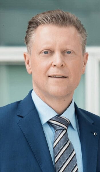 Stefan Schulze, AML-Officer bei BarmeniaGothaer, präsentiert sich in einem formellen Anzug. Im Kontext der EU-Geldwäscheverordnung setzt er auf innovative Ansätze zur Optimierung von KYC-Prozessen während der Fusion des Unternehmens.