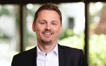 Christian Koch, Senior Vice President Cybersecurity IT/OT, Innovations & Business Development bei NTT DATA DACH, präsentiert sich in einem professionellen Umfeld. Seine Expertise in Cybersecurity und Zero Trust ist für die Banken-IT von entscheidender Bedeutung.