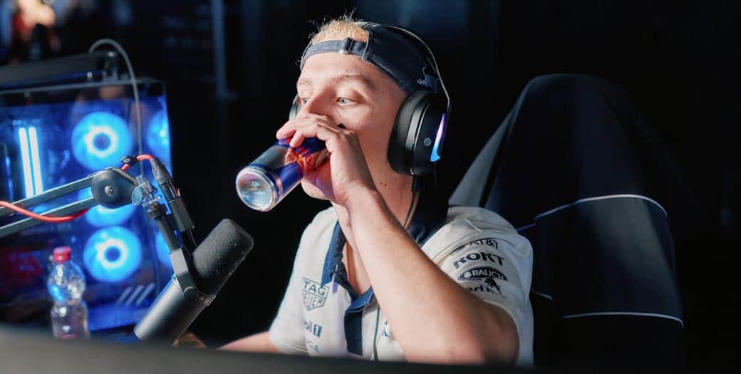 Ein Gamer mit Headset trinkt Red Bull am Mikrofon vor einem leuchtenden PC; Red Bull führt den gaming Index mit 94,3 Punkten an.