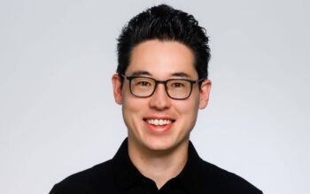 Prof. Dr. Dennis-Kenji Kipker lächelt mit schwarzer Brille und schwarzem Hemd vor hellem Hintergrund; er forscht zu digitaler Resilienz und Azure-Lock-in.