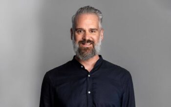 Peter Hüftlein, Head of Product bei Solaris SE, lächelt im dunklen Hemd vor grauem Hintergrund; seine Produktarbeit betrifft Konten und Transaktionen im Embedded Finance.