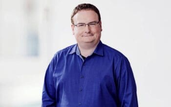 Matthias Thiele, Bereichsleiter Digital Products & Technology bei der DKB, präsentiert sich in einem blauen Hemd. Seine Verantwortung umfasst das Online Banking sowie geschäftskritische Bankplattformen und Kernbanksysteme, wobei APIs eine zentrale Rolle spielen.
