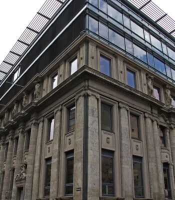 Historisches Eckgebäude mit steinernen Säulen und moderner Glasfassade; die Boerse Stuttgart Group erhält eine DLT TSS-Lizenz.